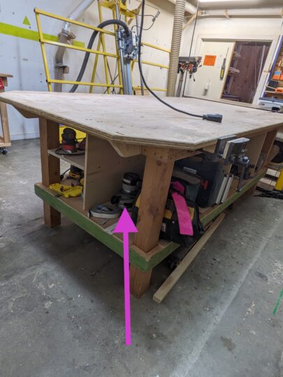 Arrow pointing to the location of the porter cable router under the work bench.