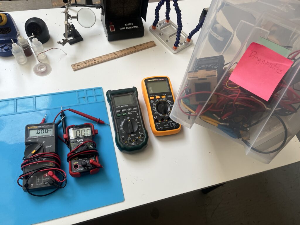 Several ACE Electronics multimeters on a table alongside the storage bin labeled "Diagnostics."