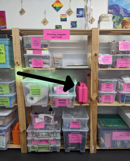 black arrow pointing to pink case on shelfs packed with bins and supplies